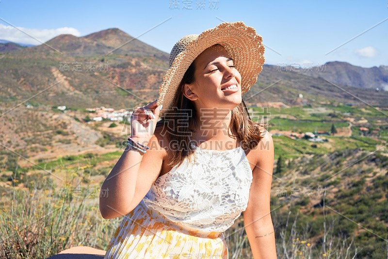 年轻美丽的女子在山上享受着暑假的风景，旅行者女孩笑得很开心