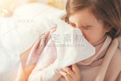 生病的女孩用纸巾捂着鼻子