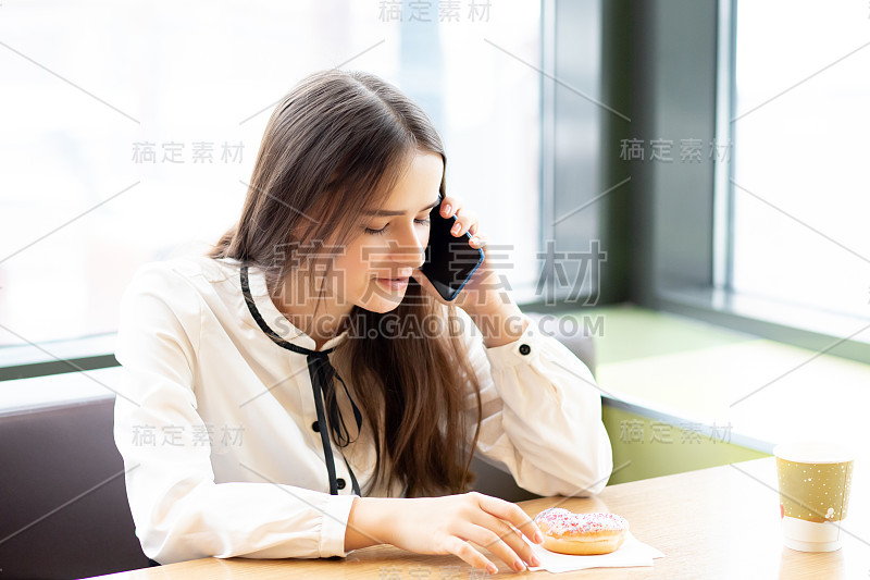 年轻的女商人在咖啡馆里拿着智能手机，谈笑风生