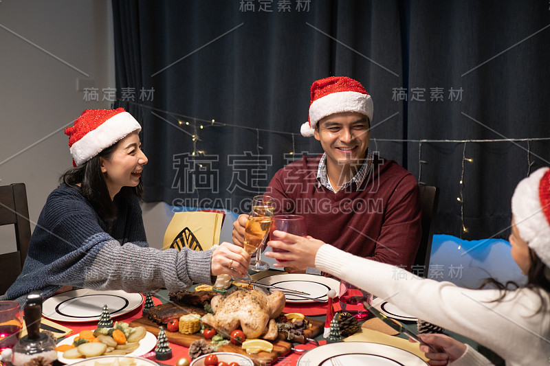 快乐的家庭在圣诞之夜在装饰着圣诞树的餐厅一起庆祝