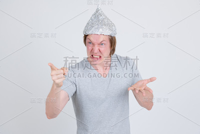 一名愤怒的年轻人戴着锡纸帽对阴谋论概念指指指