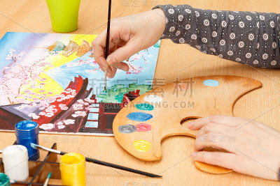 女性手用毛笔在室内画日本山水