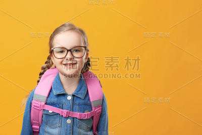 一个黄色背景上背着背包的小女生的肖像。孩子戴眼镜的特写。回到学校。教育观念。