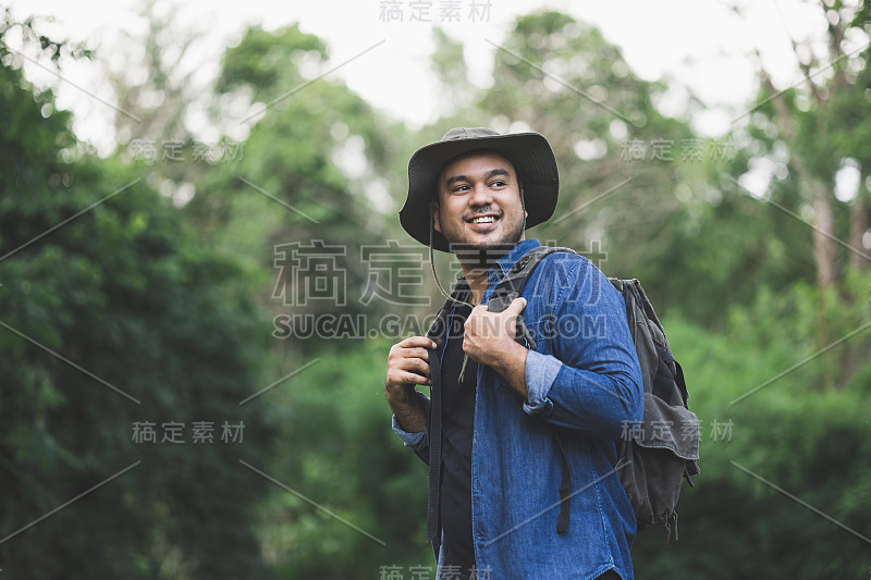 年轻帅气的男人背着背包正在独自走在路上。人们期待一次有趣的旅行。