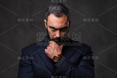 穿着灰色西装，满脸络腮胡子的严肃男性。