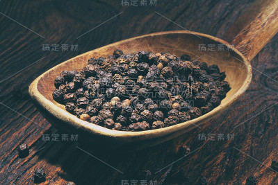 木桌上的木勺里放着黑胡椒
