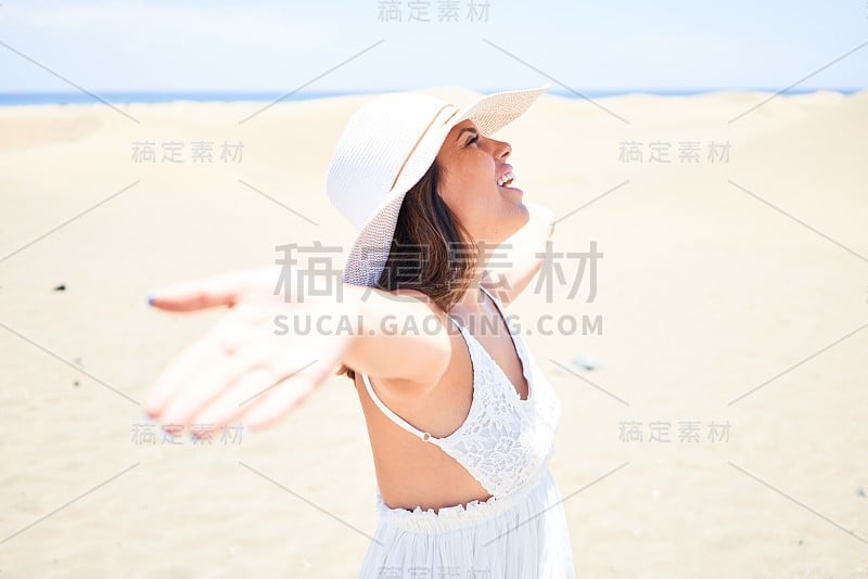 年轻美丽的女人日光浴张开双臂享受夏天在马斯帕洛马斯沙丘海滩