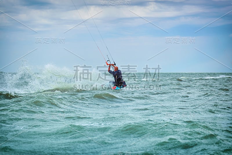 在夏天，人们骑着风筝在海浪上冲浪。