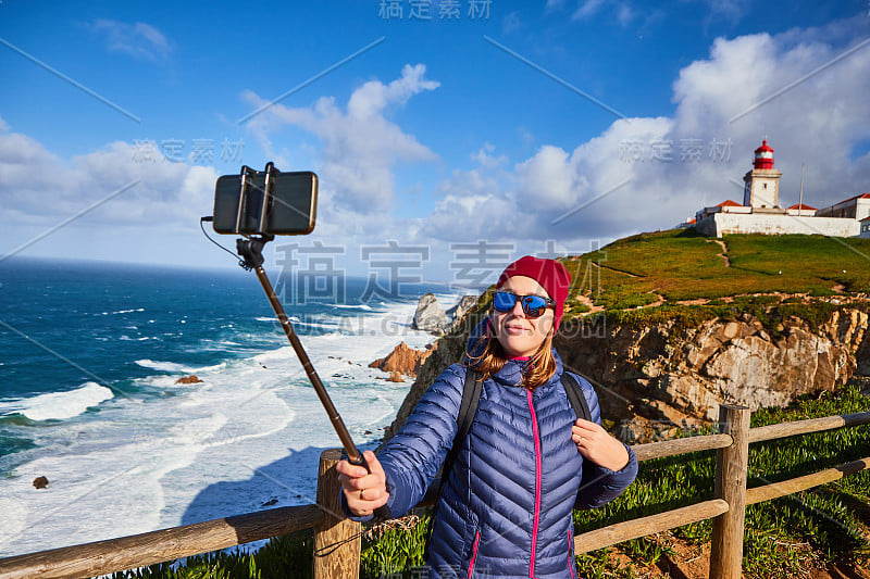 一名年轻女子在卡巴罗卡角旅游，用手机拍摄美丽的风景，葡萄牙冬季之旅。欧洲最西端