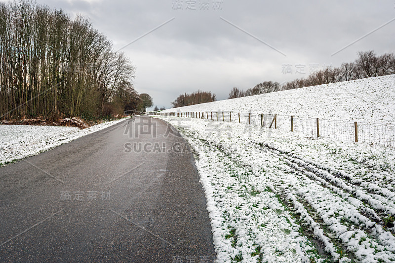 积雪覆盖的堤坝底部的柏油路