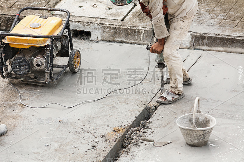 建筑工人用手提钻在混凝土表面钻孔