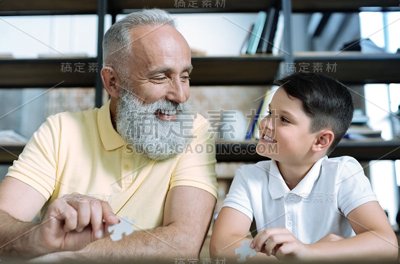 友好的老人和孙子在玩拼图游戏