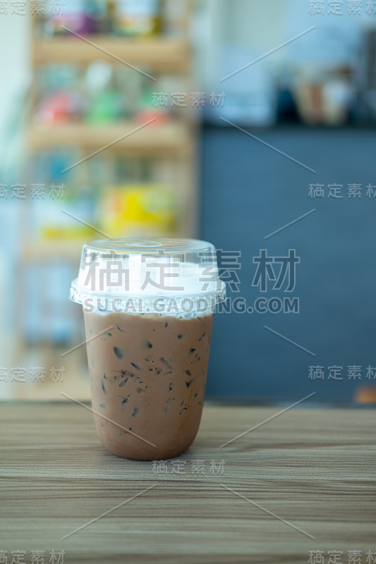 冰咖啡摩卡和泡沫牛奶塑料玻璃在木桌上