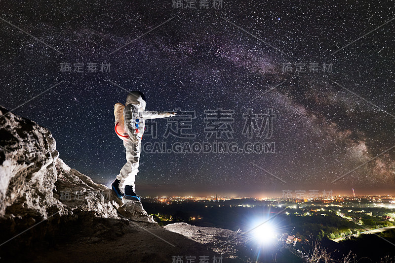 在美丽的星空下，宇航员站在岩石山上。