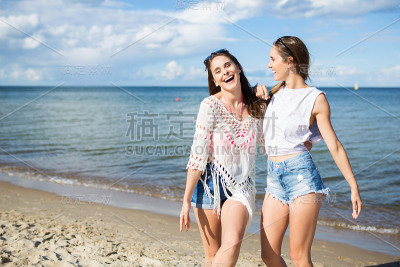 两个快乐的女性朋友一起站在沙滩上笑