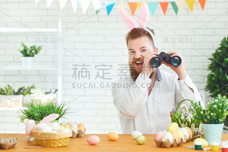 复活节快乐。一个满脸胡须、面带微笑的胖子坐在装饰着复活节的桌子前，用望远镜看东西。