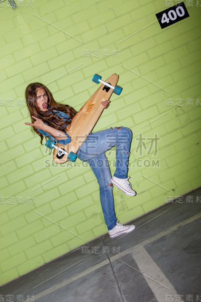 美丽的长发女子与一个木制长板靠近绿色的墙