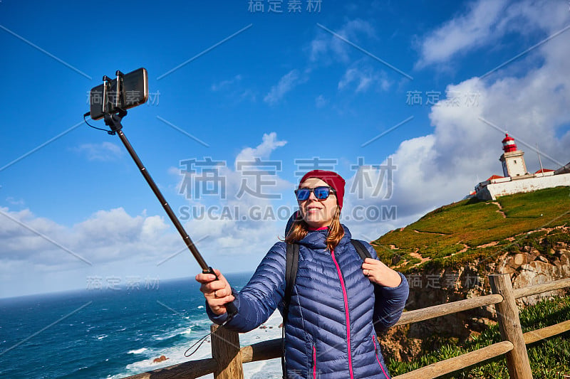 一名年轻女子在卡巴罗卡角旅游，用手机拍摄美丽的风景，葡萄牙冬季之旅。欧洲最西端