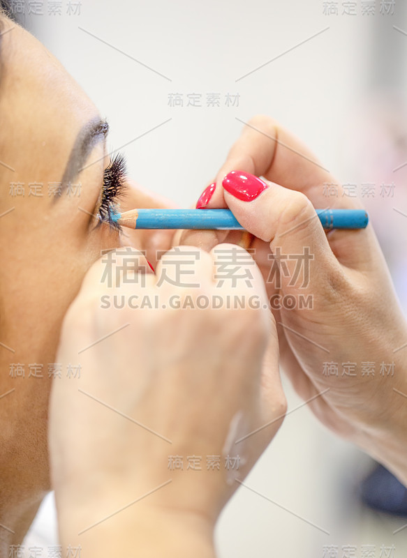 化妆师的手在女人的眼睛上化妆