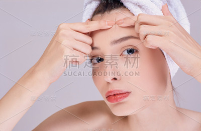 一个漂亮的黑发女子在额头上压着一个青春痘。