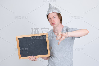 悲伤的年轻人拿着锡纸帽，拿着黑板，竖起大拇指