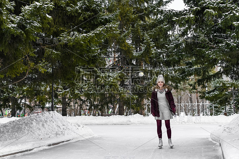 女孩在下雪的冬季公园溜冰