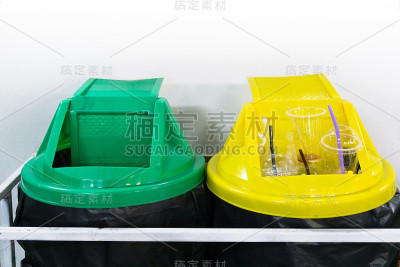 黄色和绿色的塑料垃圾回收站在白色的墙上
