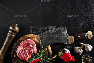 牛里脊片，用斧头切肉，调味料——迷迭香、胡椒粉、盐、大蒜。旧木板上的石头黑色桌子