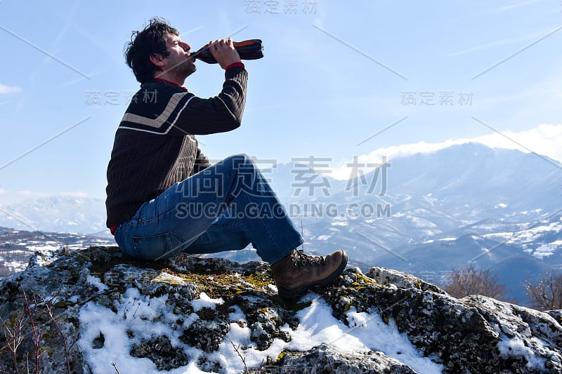 一名游客在山顶上喝着啤酒，感受着自由