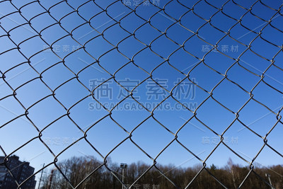 金属网有蓝天，铁栅栏上有蓝天，网眼围栏，铁链围栏外有蓝天背景