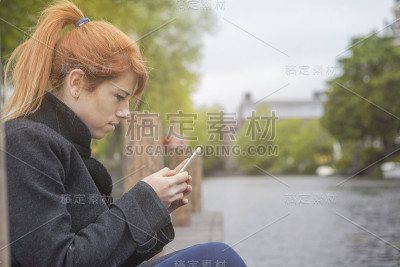 快乐女孩在城市公园用智能手机