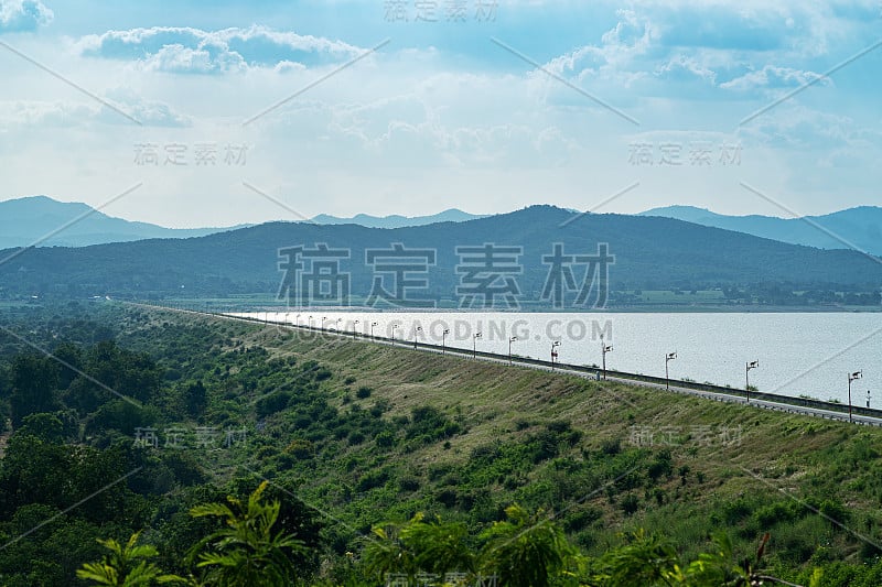 漫长的道路上的山脊与水坝和山的背景。景观。