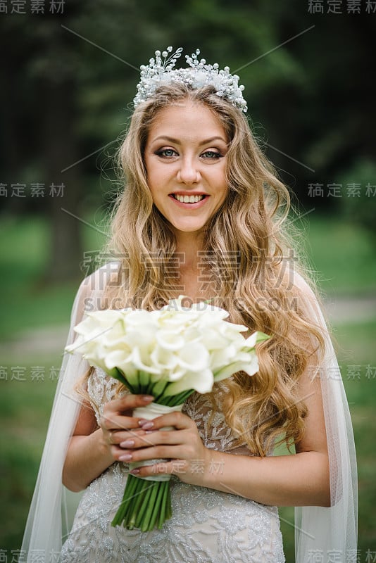 年轻美丽的女孩穿着优雅的衣服，手拿一束白色的鲜花和绿色的丝带站在大自然。新娘在户外捧着婚礼花束。