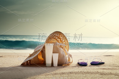 防晒霜，帽子和包在热带海滩