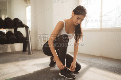 亚洲女人在健身房系鞋带
