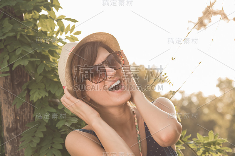 可爱的年轻女子摆姿势在户外夏天的阳光。