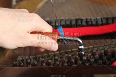 男性手和钢琴调音师。