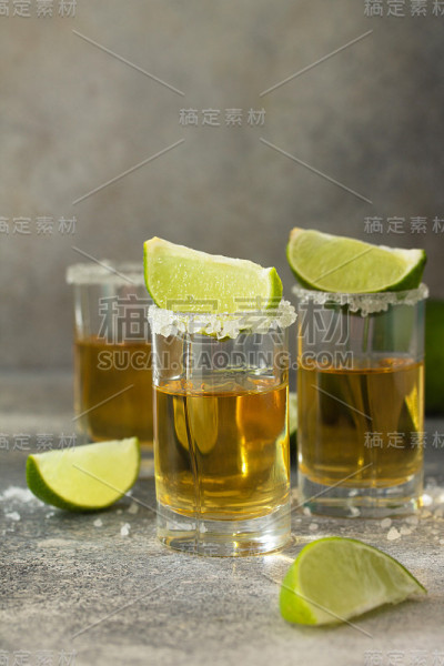 黄金龙舌兰酒。墨西哥金龙舌兰酒与石灰和盐在石头轻混凝土工作台上。