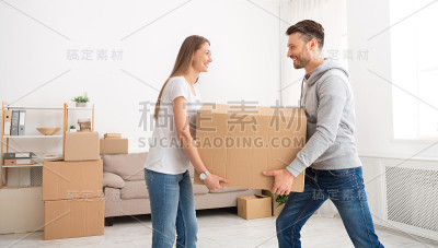 一对快乐的年轻夫妇用纸板箱搬进了新公寓