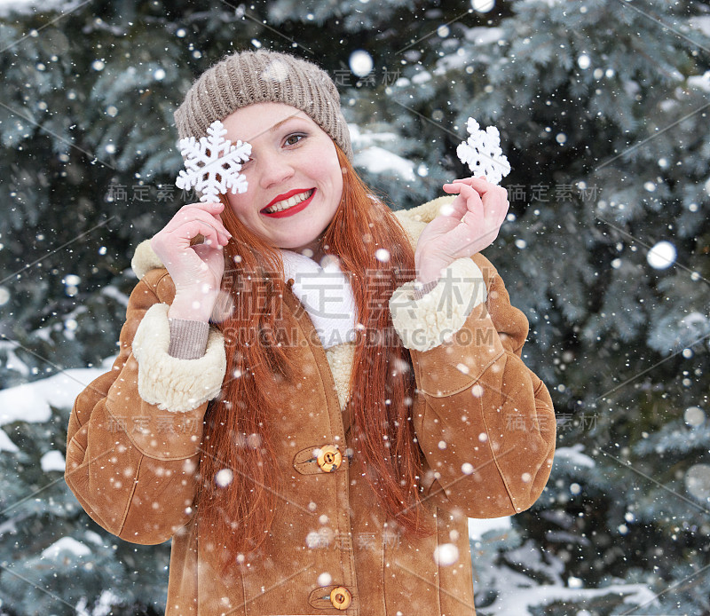 女孩肖像在冬天的户外，展示大雪花玩具。