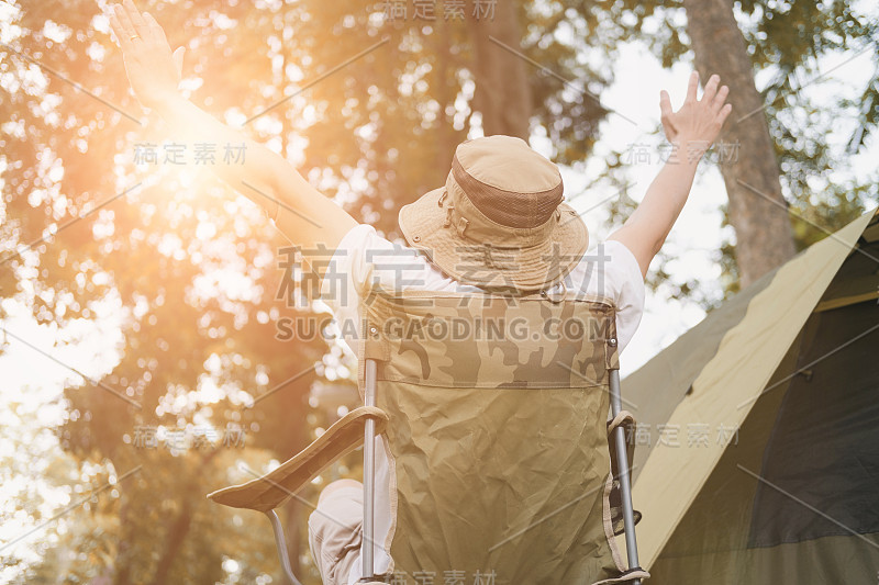 在森林露营地的帐篷前，年轻的游客坐在椅子上休息和放松。夏天的户外活动。在国家公园探险旅行。