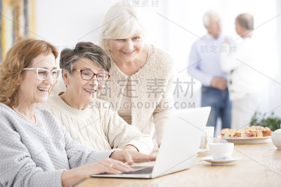 微笑着使用笔记本电脑的资深女性