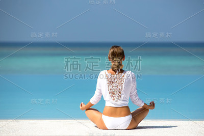 年轻女子在马尔代夫海滩上练习瑜伽