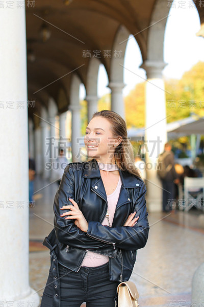 一个白人女人站在柱子旁边，背景是建筑物