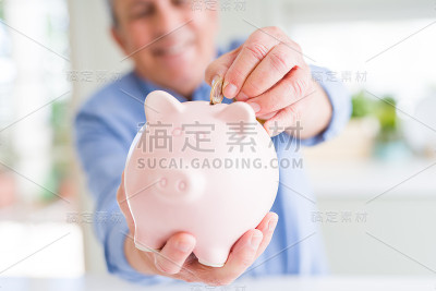 男子将硬币放入扑满，作为储蓄微笑自信