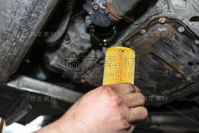 汽车技工持有一个新的机油滤清器柴油发动机在背景油底壳从发动机。