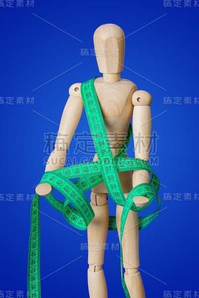 木制玩具人物与测量磁带在蓝色