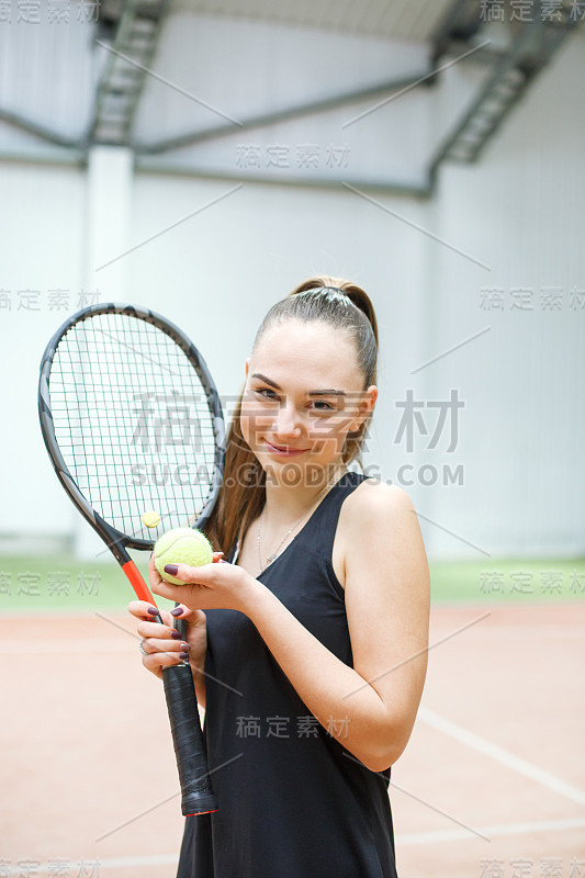 在人工照明的网球场上，一个女孩拿着网球拍看着镜头