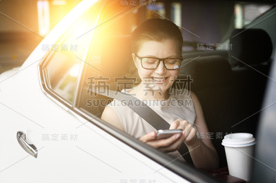 车里的女人用的是智能手机。喝饮料。