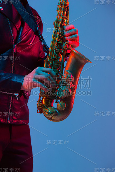 年轻的白人爵士音乐家在霓虹灯下演奏萨克斯风，特写